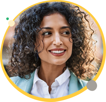 Woman smiling with dark brown curly hair looking to her right and wearing a white shirt with a teal overcoat.